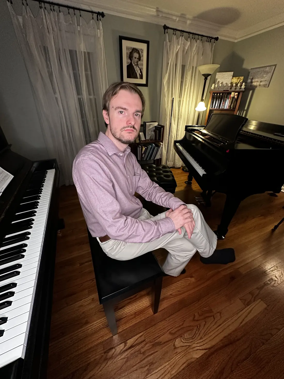 Sean Morris seated in his home studio between an upright and a grand piano