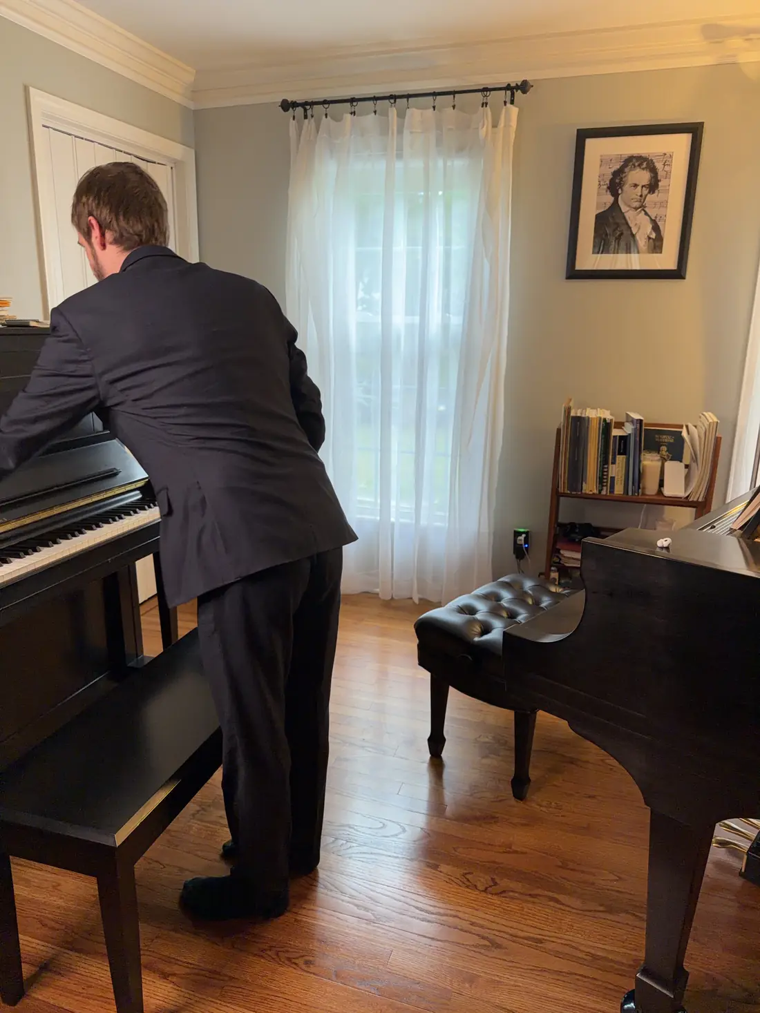 Sean at the upright piano in his teaching studio, grand piano in the foreground