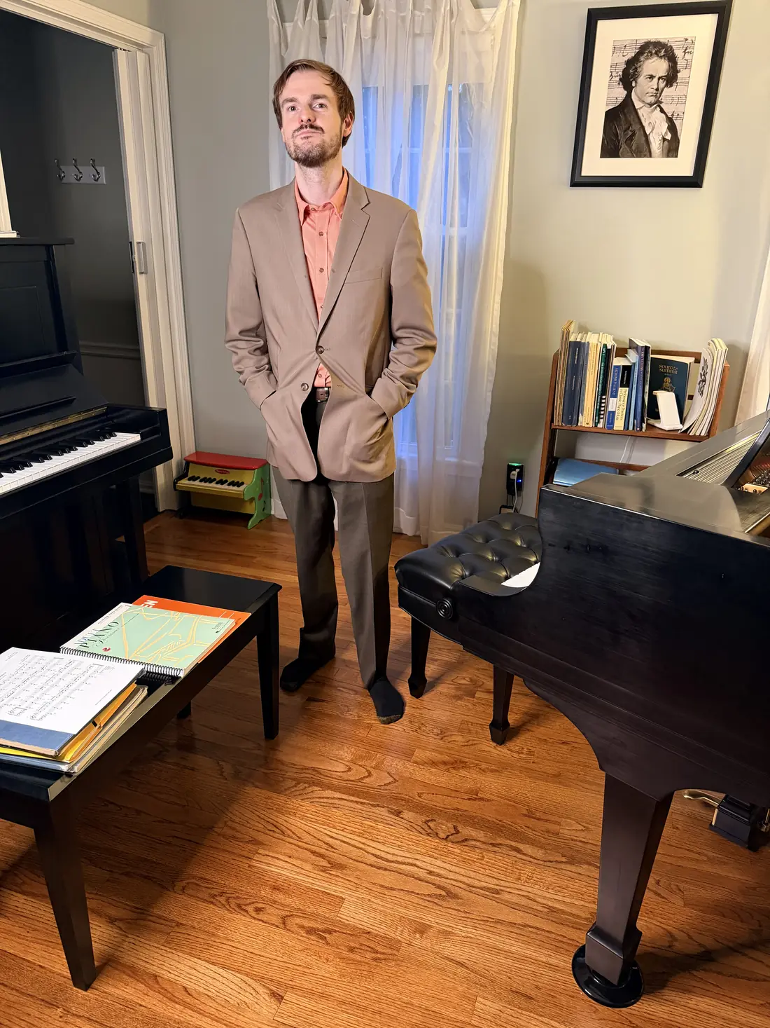 Sean standing in his studio between the upright and the grand piano
